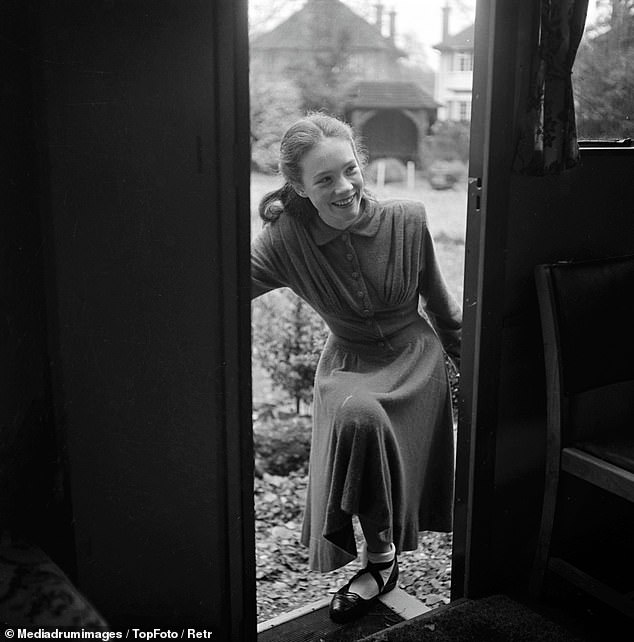Belleza: una Julie sonriente aparece en un vestido de manga larga caminando por la puerta principal.