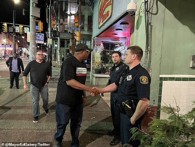 Gainey le da la mano a los policías locales durante su paseo por el South Side.  Un juez local pidió que se declare un 