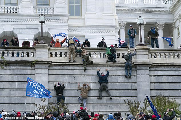 Los partidarios del entonces presidente Donald Trump escalan el muro oeste del Capitolio de los Estados Unidos en Washington durante el levantamiento del 6 de enero.