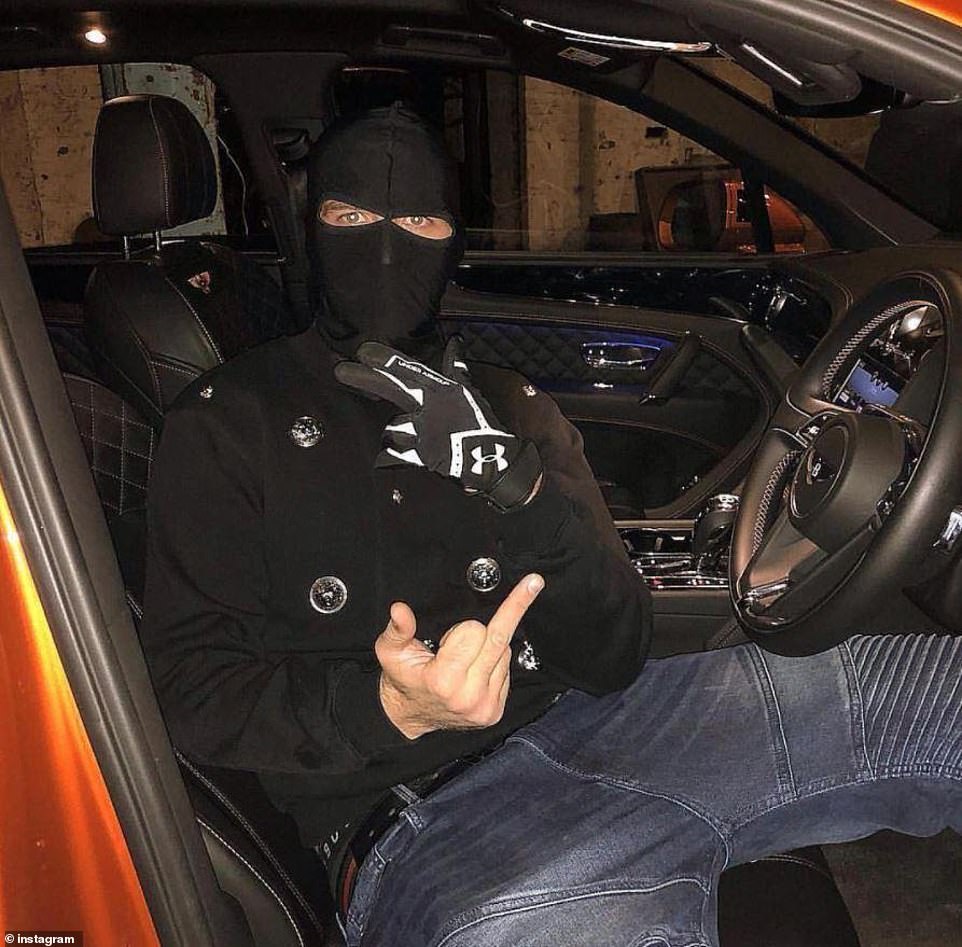 Un pandillero posa con el dedo medio hacia arriba en un Bentley naranja.  El grupo tiene vínculos con la mafia en Albania, lo que les proporciona un suministro directo de cocaína de los cárteles de la droga sudamericanos.