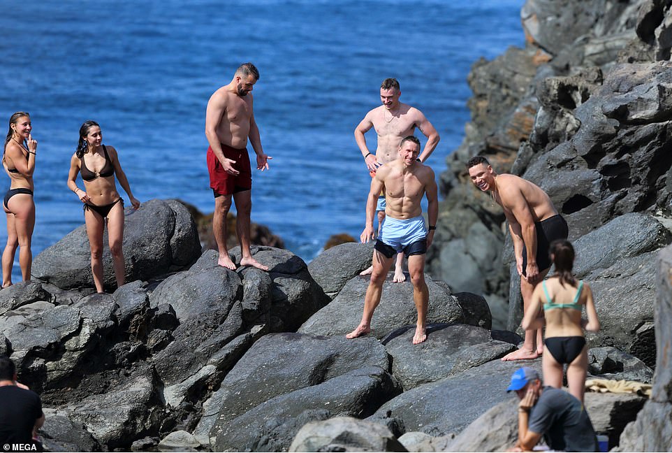 Amigos cercanos se unieron a la feliz pareja mientras escalaban una pila de rocas con vista al Océano Pacífico.