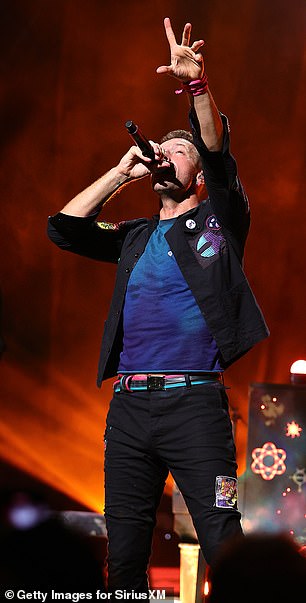Chris vistiendo una camiseta azul marino y pantalones negros con un elegante parche multicolor.