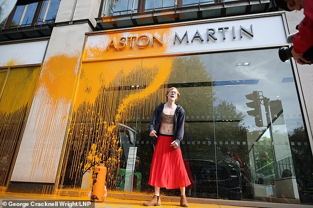 Un activista de Just Stop Oil rocía pintura naranja en una tienda de Aston Martin en Park Lane mientras otros miembros de Just Stop Oil bloquean las carreteras cerca de Park Lane